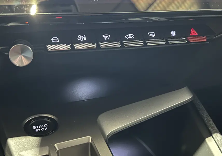 Détail du tableau de bord de la Peugeot 308 blanc Okenite, avec boutons de commande et bouton Start/Stop visible.