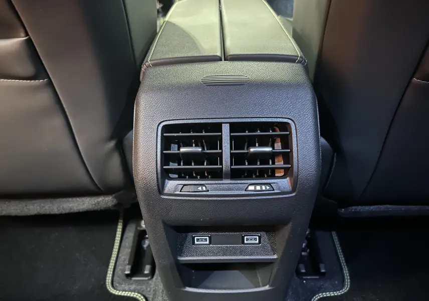 Vue rapprochée de la console arrière noire avec aérateurs et ports USB de la Peugeot 308 blanche Okenite.