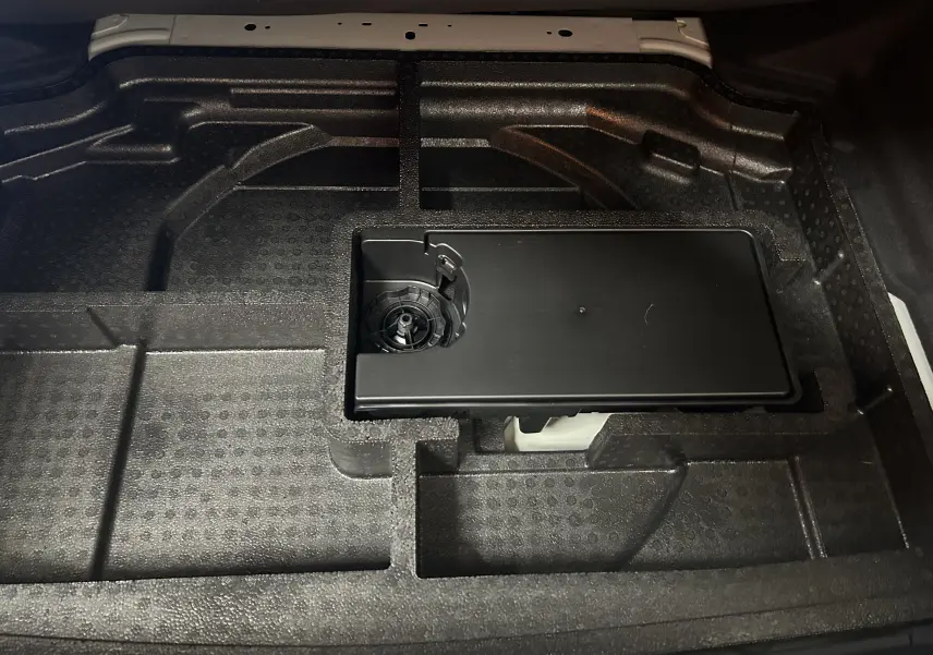 Gros plan sur le rangement en mousse noire sous le coffre de la Peugeot 308 III Ph.2 Hybrid 145 GT blanc Okenite.