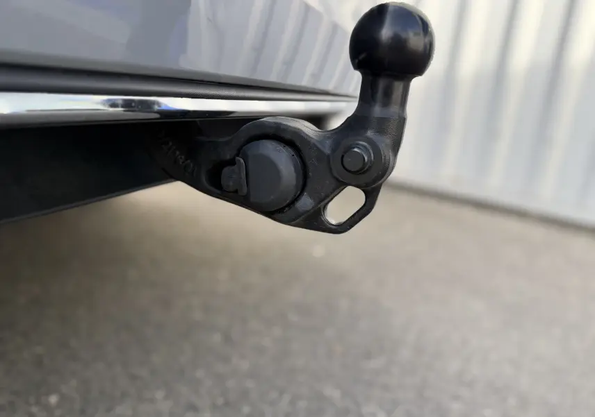 Gros plan sur l'attelage noir fixé à l'arrière d'une Volkswagen Golf SW gris lunaire, visible en partie.