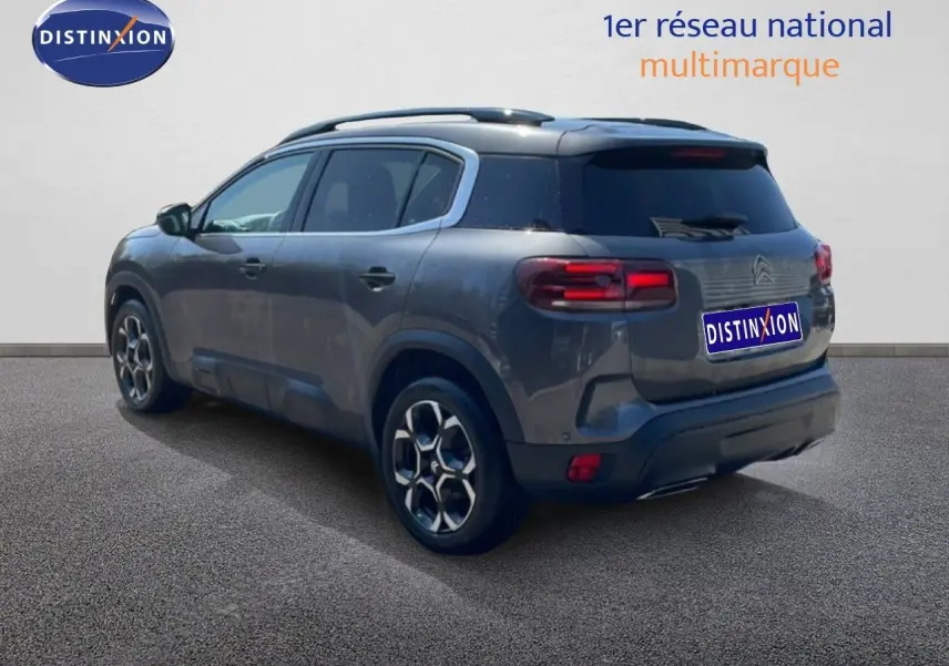 Vue 3/4 arrière droite d'un Citroën C5 Aircross gris platinium métal avec jantes bi-ton et toit noir.