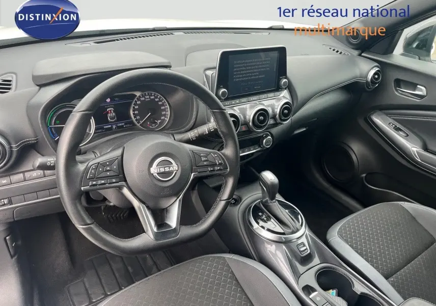 Intérieur noir du Nissan Juke 2024, vue du poste de conduite avec volant multifonction et écran tactile central.