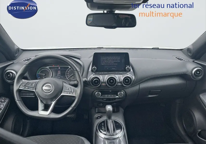 Tableau de bord et volant noir du Nissan Juke 2024, vue frontale intérieure avec écran tactile central et aérateurs ronds.