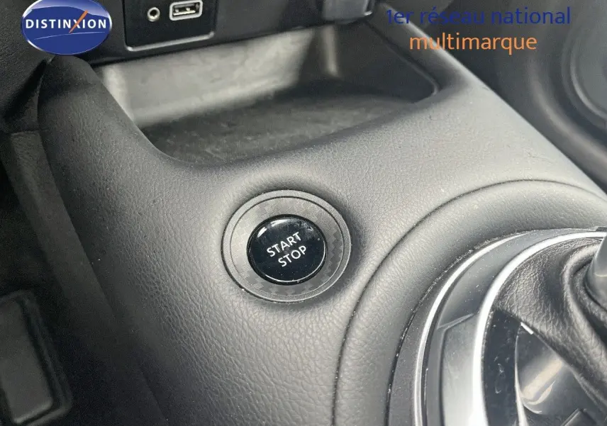 Bouton start/stop en gros plan sur la console centrale noire du Nissan Juke blanc nacré 2024 hybride.