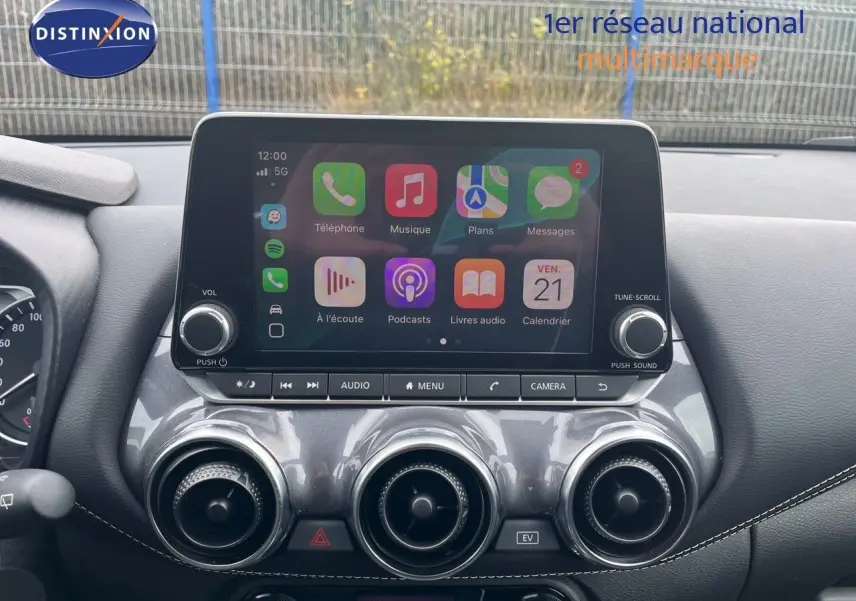 Écran tactile central avec interface Apple CarPlay sur tableau de bord gris du Nissan Juke blanc nacré 2024.