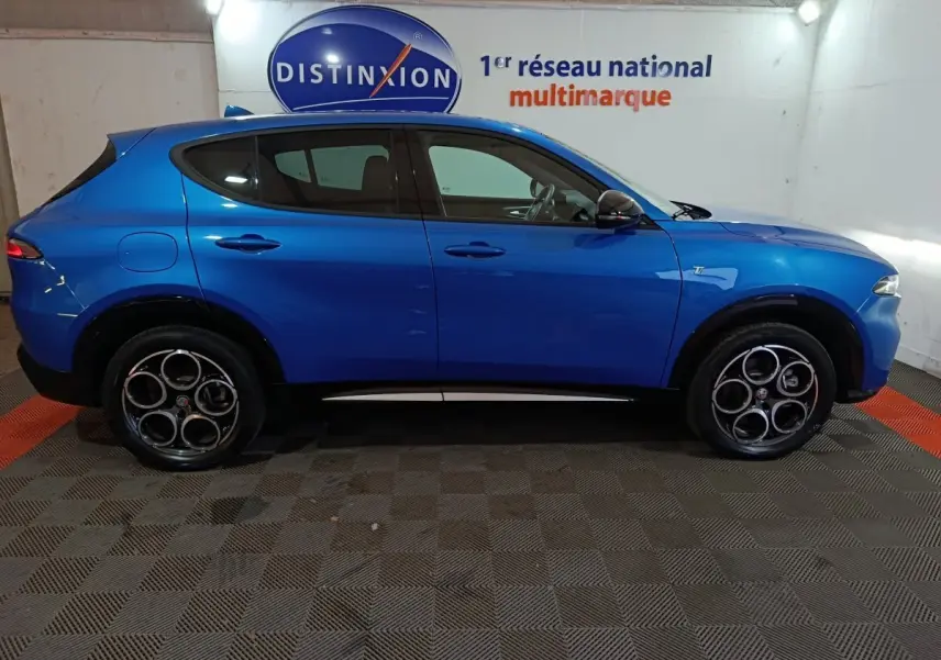 Profil droit d'un Alfa Romeo Tonale bleu 2023 avec jantes distinctives à cinq cercles et détails noirs contrastants.