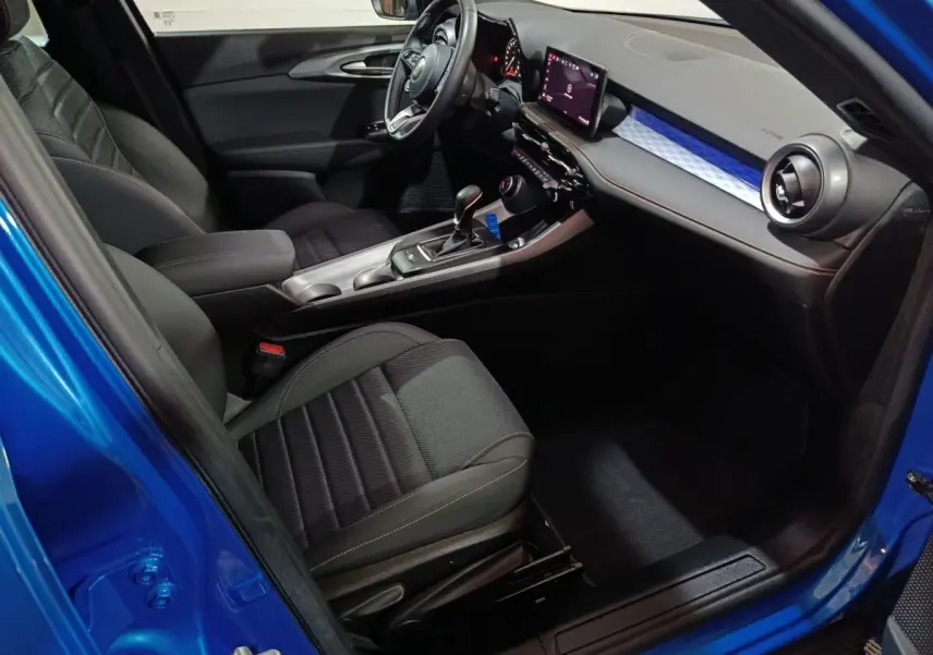 Vue intérieure côté conducteur de l'Alfa Romeo Tonale bleu, avec tableau de bord digital et sièges noirs.