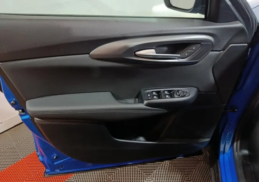 Vue intérieure côté gauche de la porte avant bleu de l'Alfa Romeo Tonale avec commandes de vitres et poignée argentée.