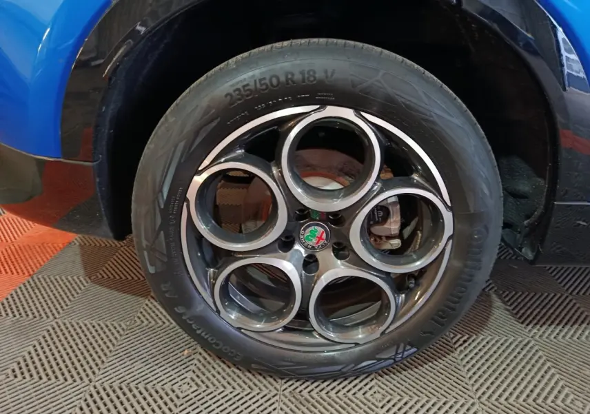 Gros plan sur la roue arrière droite d'une Alfa Romeo Tonale bleu 2023, avec passage de roue noir brillant.