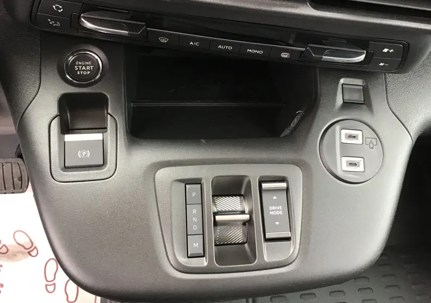 Vue rapprochée du tableau de bord central du Peugeot Partner blanc 2026, avec bouton start/stop et commandes de boîte auto.