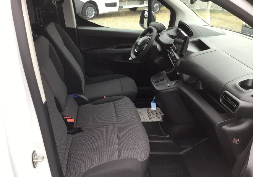 Vue intérieure côté conducteur du Peugeot Partner blanc 2026, montrant les sièges avant et le tableau de bord moderne.