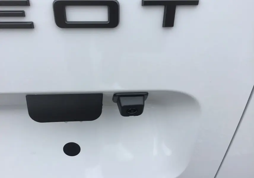 Gros plan sur la caméra de recul noire intégrée à la porte arrière blanche du Peugeot Partner XL 2026.