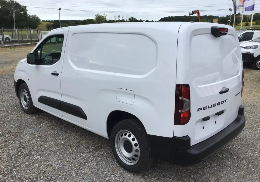 Vue 3/4 arrière droite d'un utilitaire Peugeot Partner blanc, avec porte latérale pleine et pare-chocs noirs.