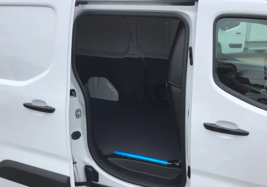 Vue latérale droite du Peugeot Partner blanc 2026 avec porte coulissante ouverte montrant l'espace de chargement vide.