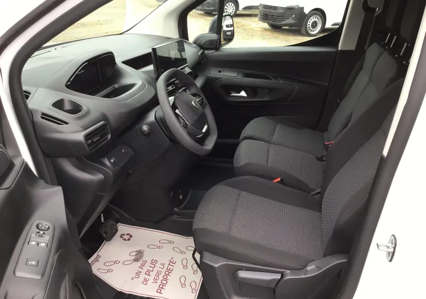 Vue intérieure côté conducteur du Peugeot Partner blanc 2026, montrant les sièges avant et le tableau de bord moderne avec écran tactile.
