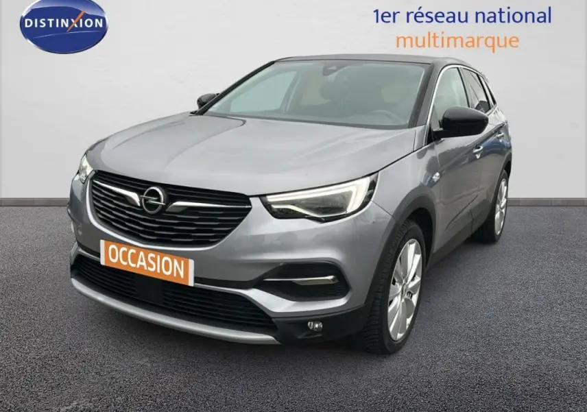 Opel Grandland X gris clair vu en 3/4 avant droit avec jantes alliage 19 pouces et phares LED allumés.