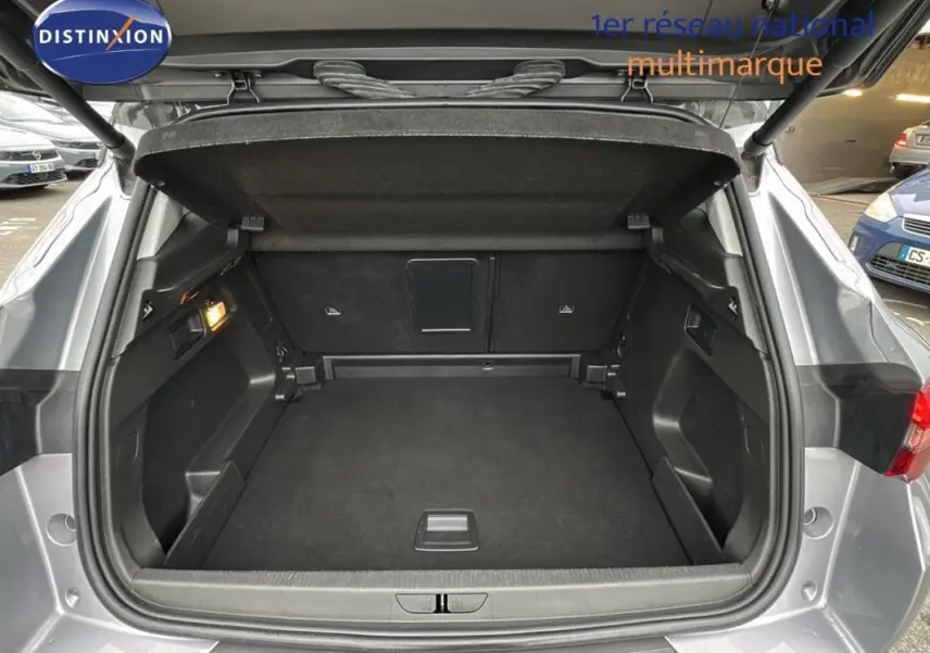 Coffre ouvert vu de l'arrière d'un Opel Grandland X gris clair, montrant un espace de chargement propre et spacieux.