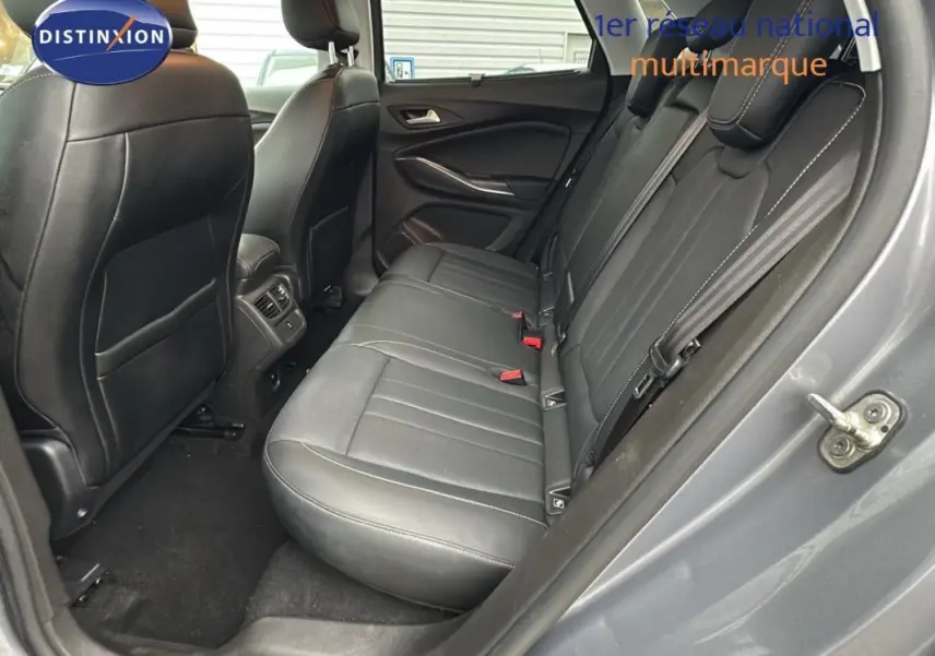 Vue côté droit de l'habitacle arrière d'un Opel Grandland X gris clair avec sièges en cuir noir et coutures blanches.