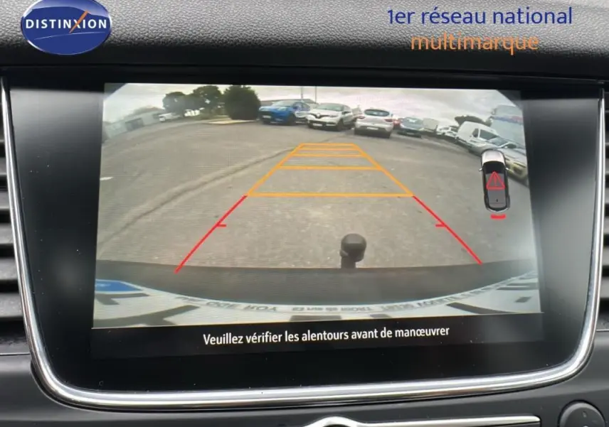 Écran tactile intérieur montrant la caméra de recul d'un Opel Grandland X gris clair avec attelage visible.
