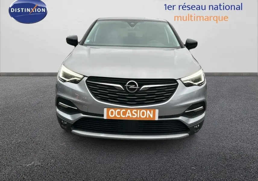 Vue frontale d'un Opel Grandland X gris clair avec phares LED allumés et plaque "OCCASION" visible.