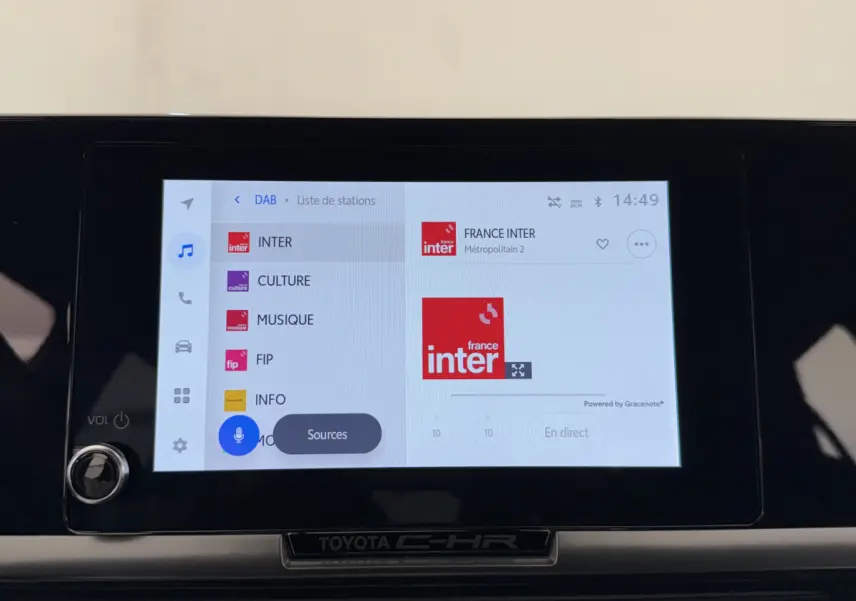 Écran tactile central du Toyota C-HR blanc 2024 affichant les stations radio numériques avec interface moderne.