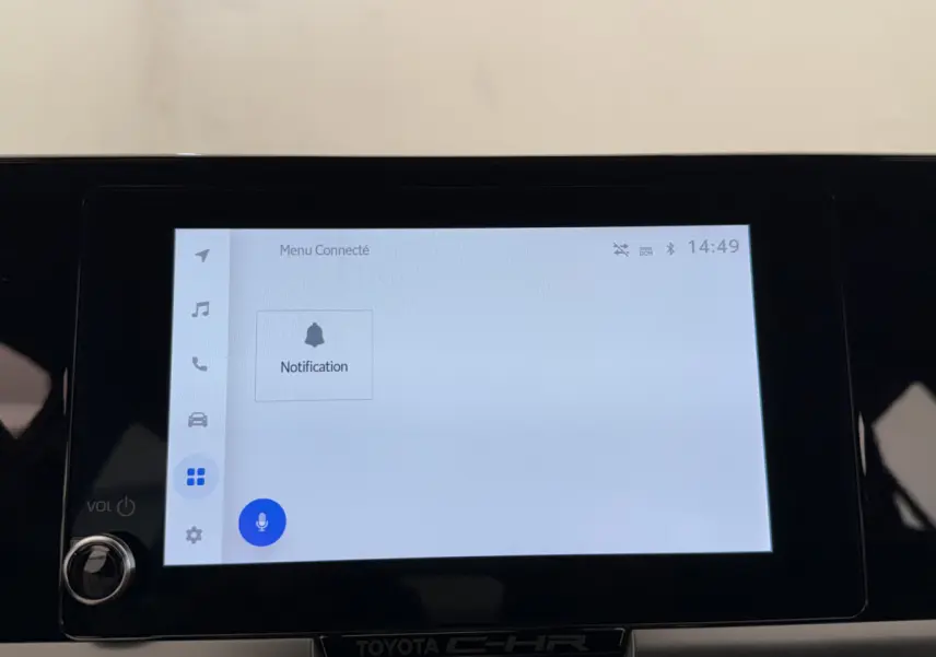 Écran tactile central du Toyota C-HR blanc 2024 affichant le menu connecté avec notification et commande vocale.