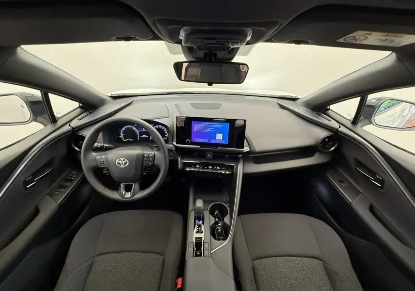 Vue intérieure avant du Toyota C-HR 1.8 Hybride blanc, tableau de bord moderne avec écran tactile central et volant multifonctions.