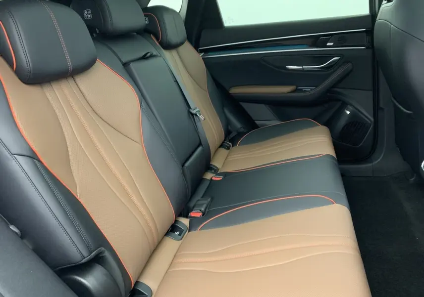 Gros plan sur le volant et le tableau de bord numérique du BYD SEAL U 2025, intérieur noir avec surpiqûres rouges.