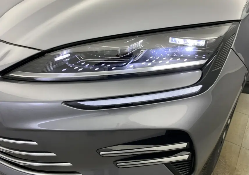 Vue arrière du coffre ouvert du BYD SEAL U 2025 gris TIME GREY, avec cache-bagages et sièges arrière noirs à surpiqûres rouges visibles.