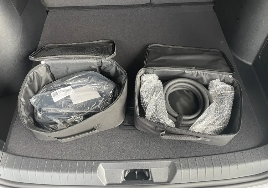 Vue du coffre du BYD SEAL U 2025 avec deux sacs de rangement noirs contenant câbles de recharge, intérieur gris foncé.