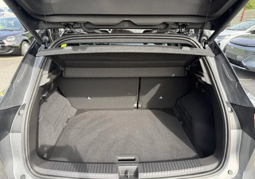 Coffre ouvert vu de l'arrière d'un Renault Austral gris Schiste satin avec cache-bagages et intérieur noir.