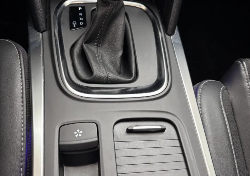 Gros plan sur la console centrale noire avec levier de vitesse automatique et commandes électroniques d'une Renault Mégane bleu 2023.