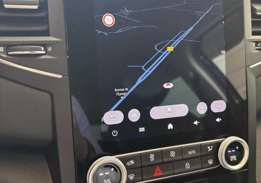Vue rapprochée du tableau de bord central tactile de la Renault Mégane bleu 2023 avec commandes climatisation et navigation affichées