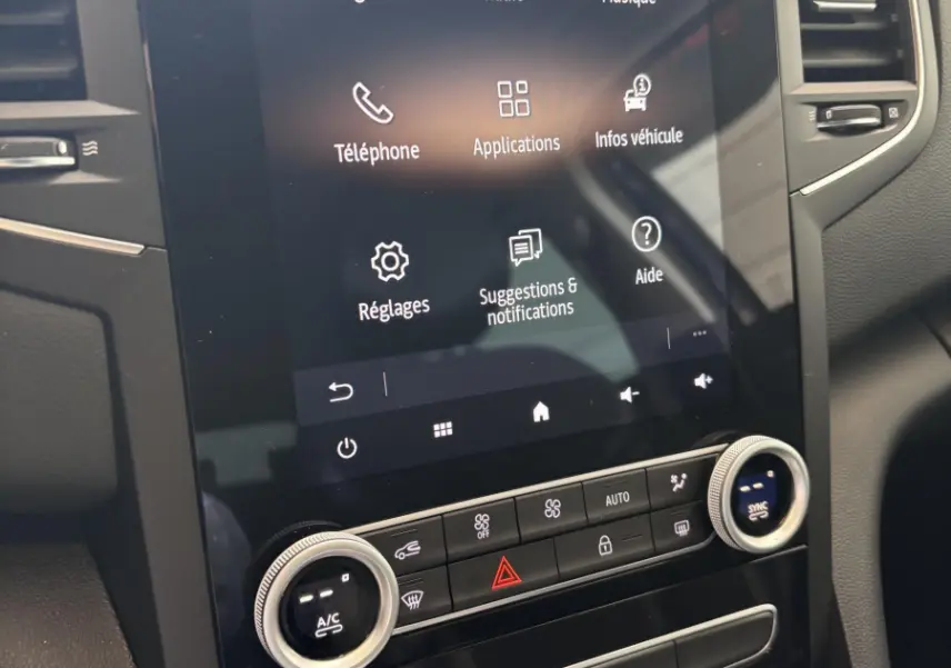 Vue rapprochée de l’écran tactile central et commandes de climatisation du tableau de bord de la Renault Mégane bleu 2023.