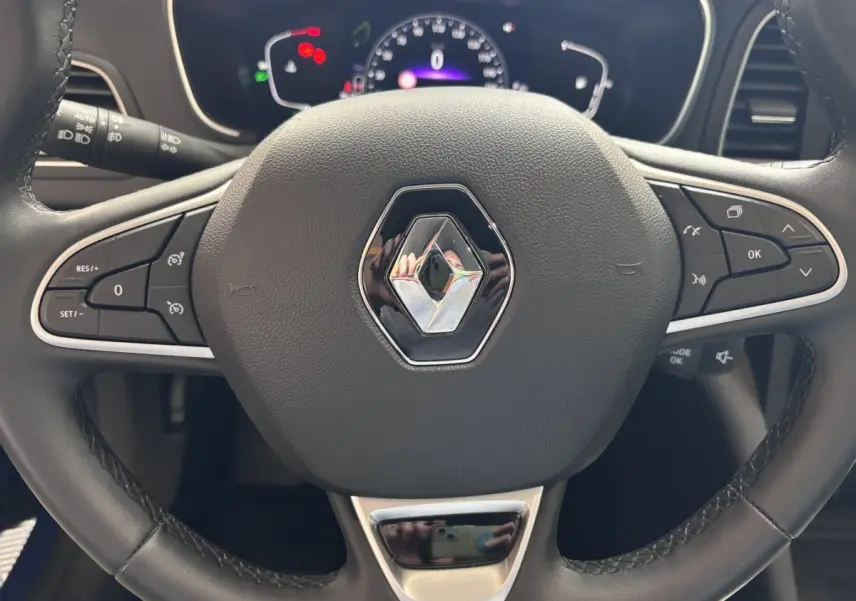Volant noir de Renault Megane 2023 techno Blue dCi 115 EDC avec commandes multifonctions et tableau de bord numérique.