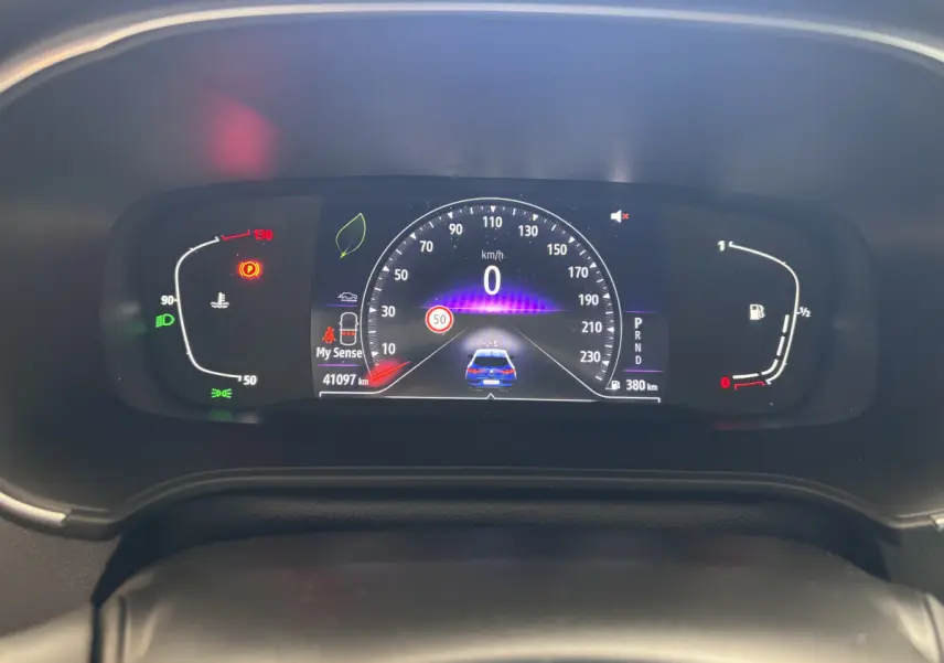 Tableau de bord numérique de la Renault Mégane 2023 bleu, affichant vitesse, jauges et alertes au centre de l'habitacle.