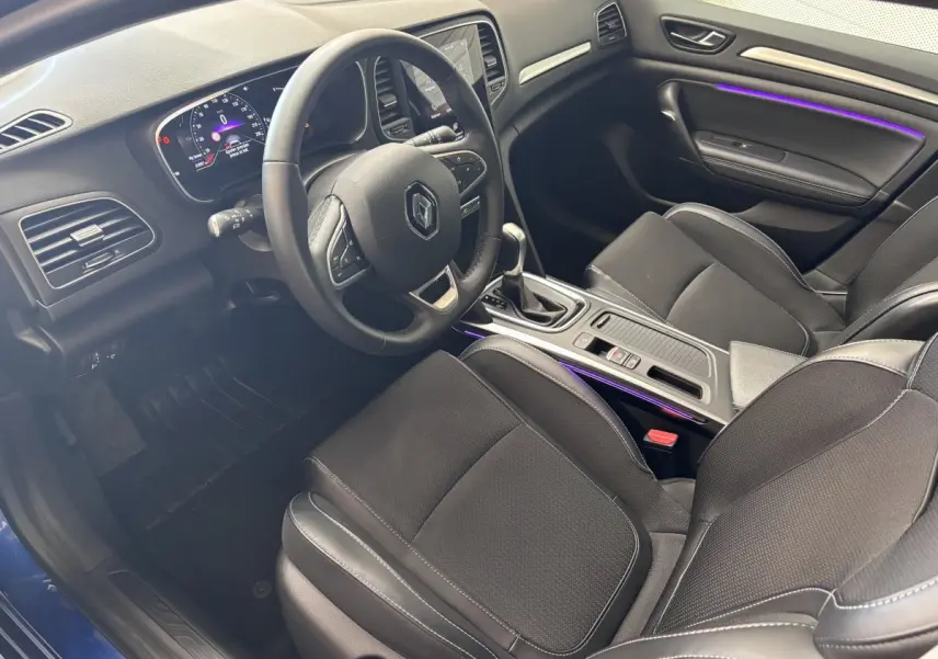Intérieur de la Renault Mégane 2023 vue côté conducteur, volant multifonctions et éclairage d'ambiance violet visible.