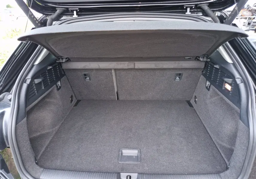 Coffre ouvert vu de l'arrière d'un Audi Q2 noir mito metal, montrant un espace de chargement propre et spacieux.
