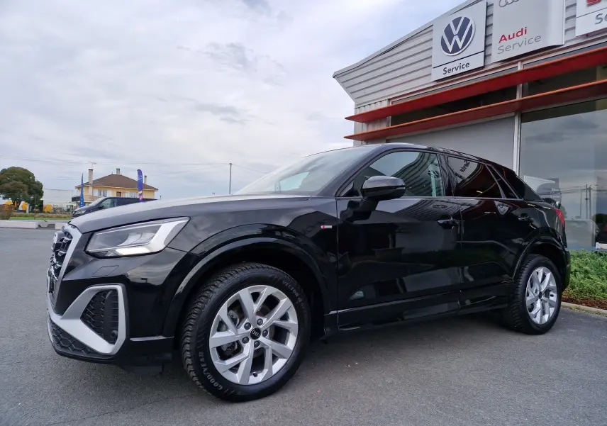 Audi Q2 noir mito metal vue 3/4 avant droit, mettant en valeur ses jantes alliage et son design compact urbain.