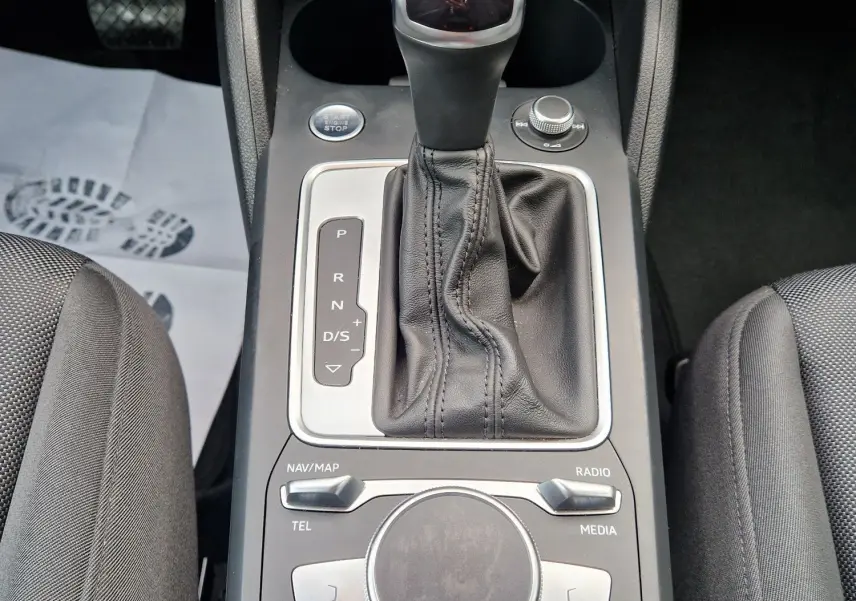 Gros plan sur la console centrale noire de l'Audi Q2 35 TFSI 2023 avec levier de vitesse automatique et commandes multimédia.