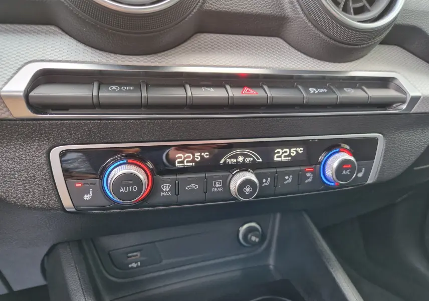 Gros plan sur la console centrale de l'Audi Q2 2023, avec climatisation automatique et commandes en noir et chrome.