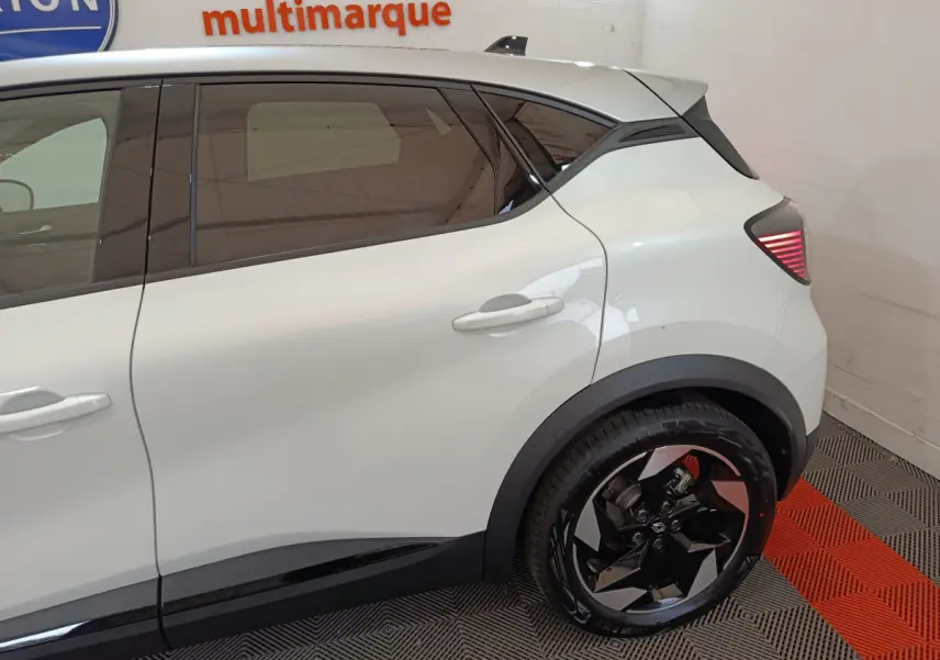 Vue latérale droite du Renault Captur blanc 2025, mettant en valeur la porte arrière et la roue arrière au design moderne.