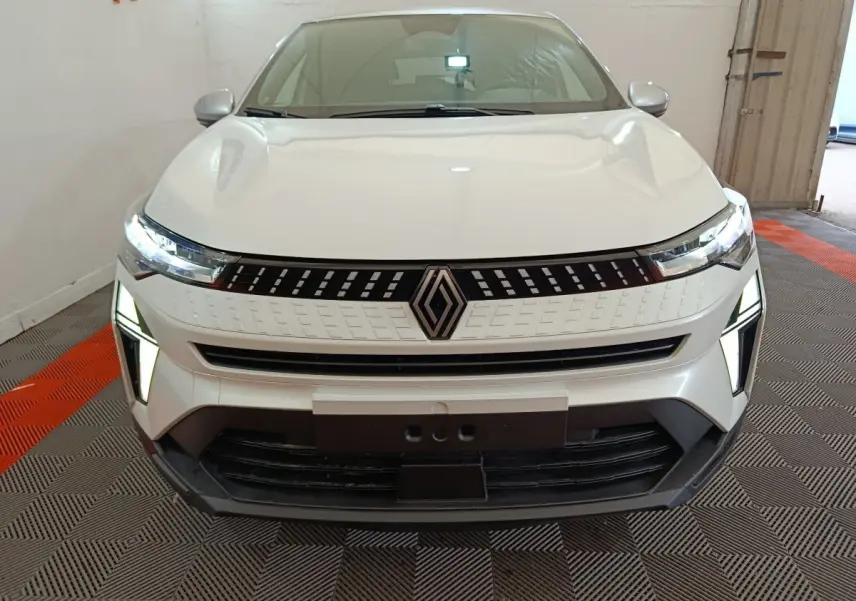 Vue frontale du Renault Captur blanc 2025 avec phares LED et calandre au design moderne dans un garage.