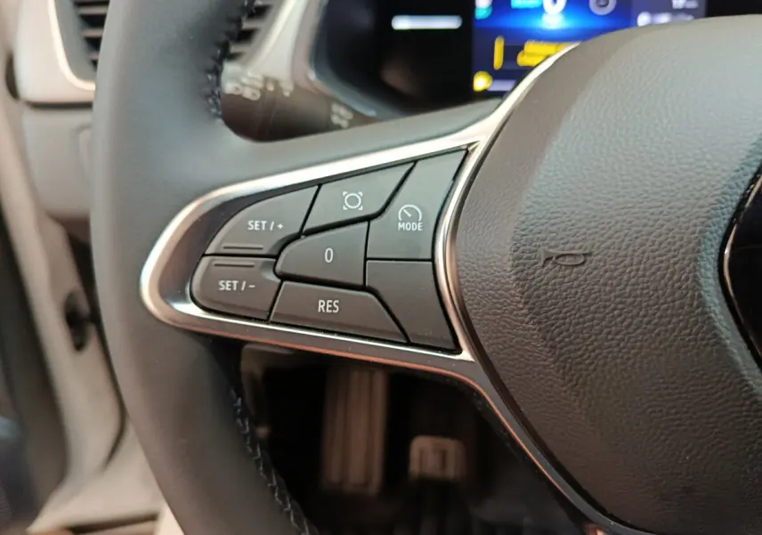 Gros plan sur les commandes du volant côté gauche du Renault Captur blanc 2025 avec affichage numérique en arrière-plan.