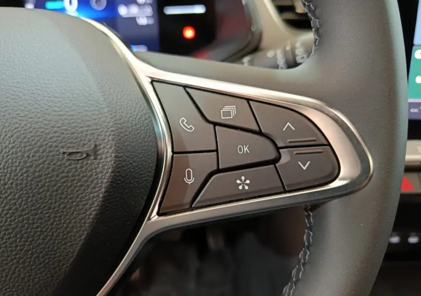 Gros plan sur les commandes multifonctions à droite du volant cuir du Renault Captur blanc techno E-Tech 2025.