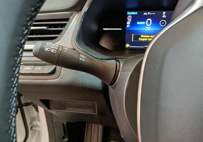 Gros plan sur la manette de clignotants et le combiné numérique bleu du tableau de bord du Renault Captur blanc 2025.