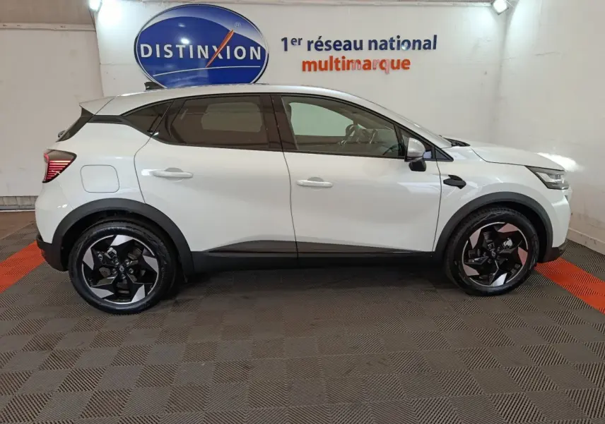 Profil latéral gauche d'un Renault Captur blanc 2025 avec jantes noires et détails noirs contrastants.