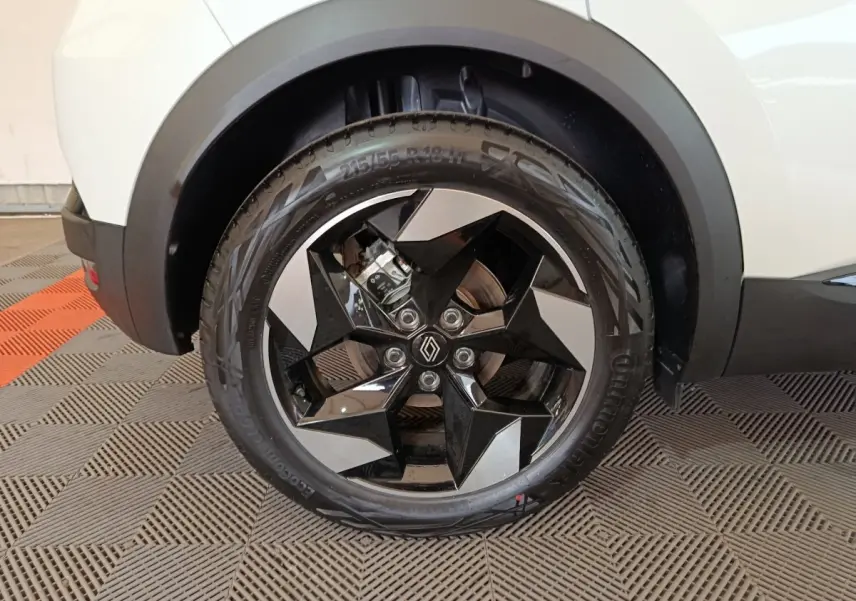 Gros plan sur la roue avant droite du Renault Captur blanc 2025, avec jante noire et argentée au design géométrique.