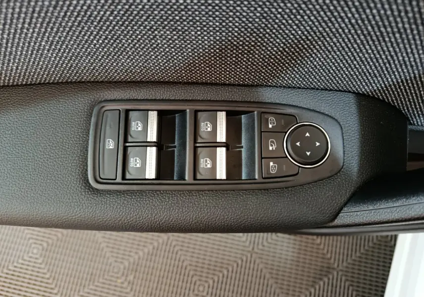 Commande des vitres électriques et réglage des rétroviseurs sur la porte côté conducteur du Renault Captur blanc 2025.