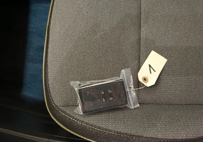 Gros plan sur la clé noire emballée posée sur un siège tissu gris foncé du Renault Captur blanc 2025.